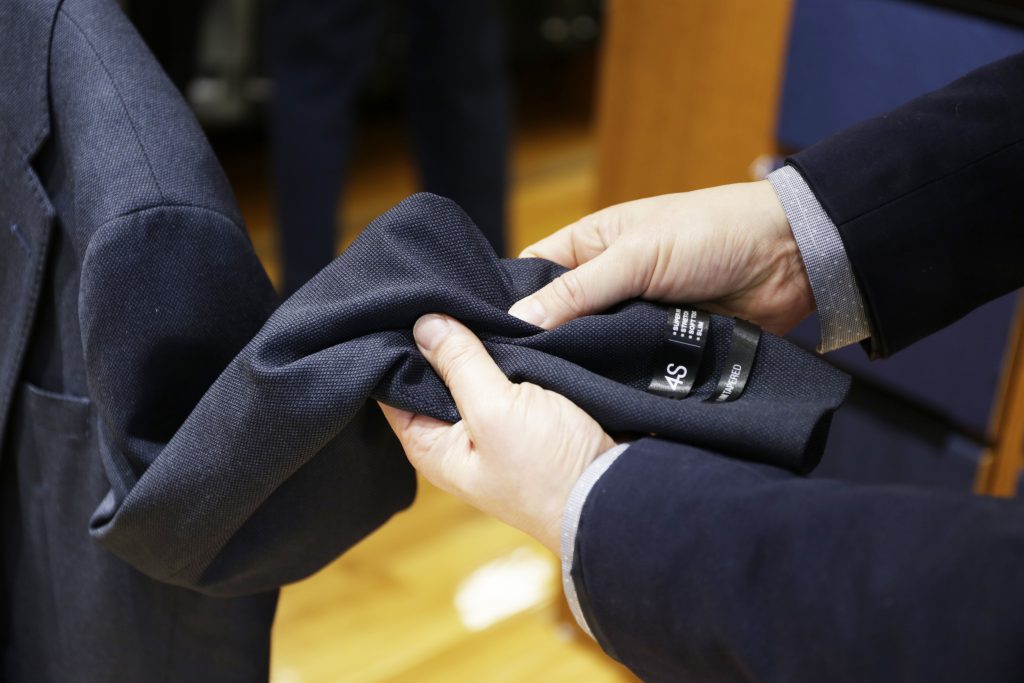 4Sオーダースーツのネイビースーツの袖部分の触り心地を確認している画像